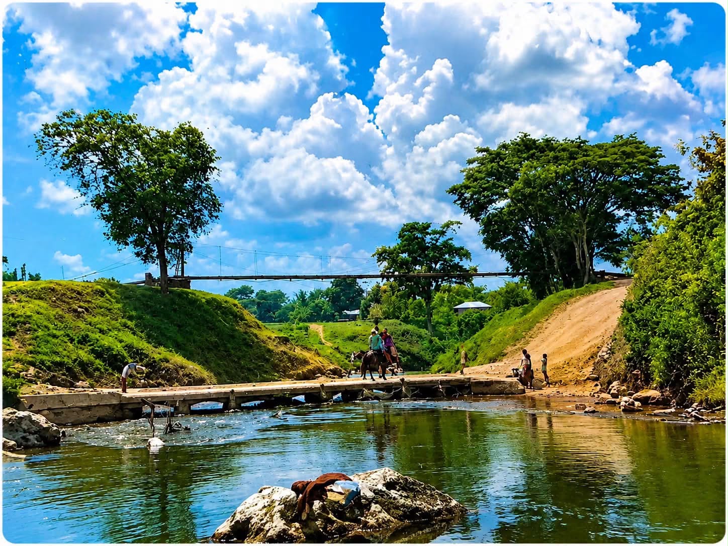 Puente sobre el río en Machaquilá con personas cruzando y puente de hamaca al fondo